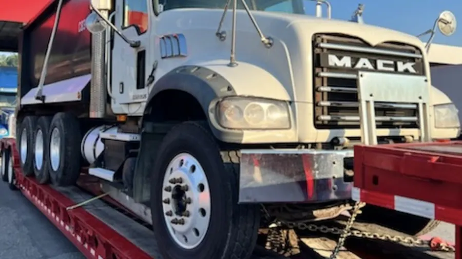 Mack dump truck chained down on a lowboy trailer